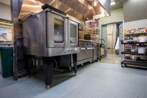 The Castle Café kitchen at Calgary Academy featuring industrial ovens, stainless steel counters, and equipment used in the Foods program.