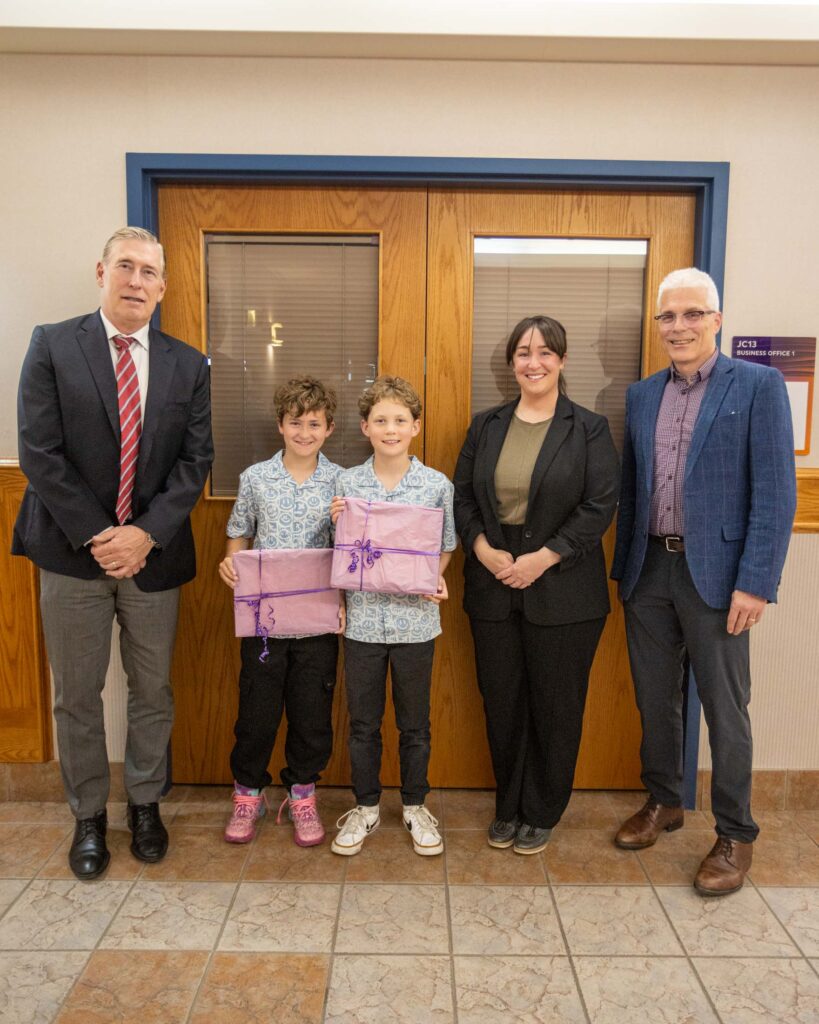Grade 4 students Zeke and River receive the Student Showcase Award, holding gifts alongside Calgary Academy staff.