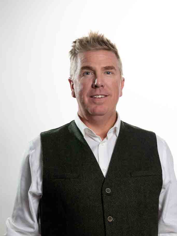 A Calgary Academy Board member smiles for a photo in front of a white background.
